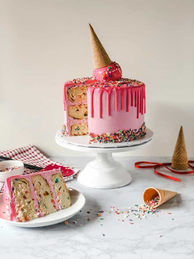 Pink drip birthday cake topped with an ice cream cone